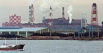 a ship and some smoking chimneys of chemical industry at the shore