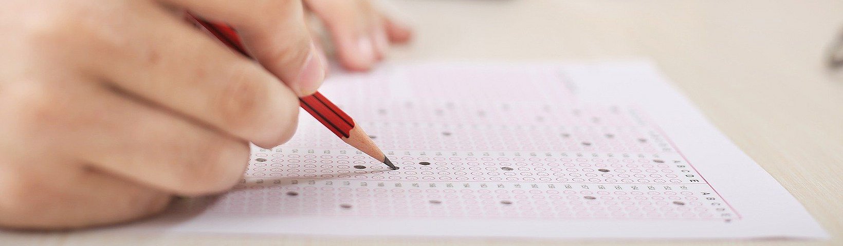 Hand mit Bleistift füllt ein Formular aus 