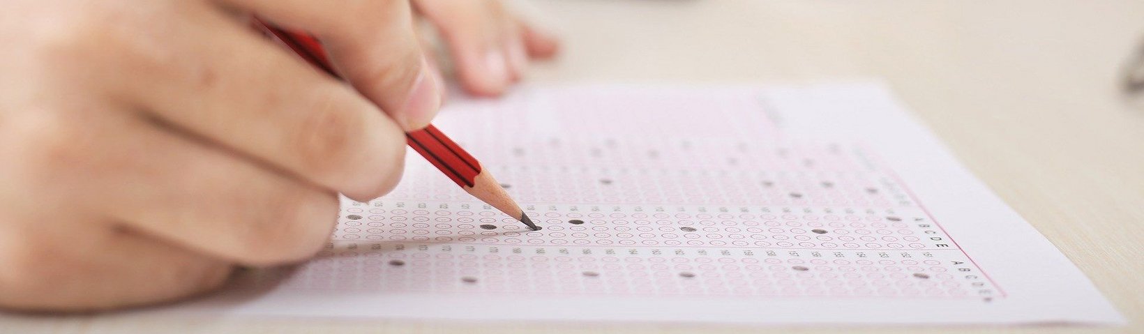 Hand mit Bleistift füllt ein Formular aus