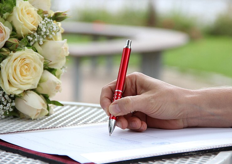 Hand mit Stift zur Unterschrift