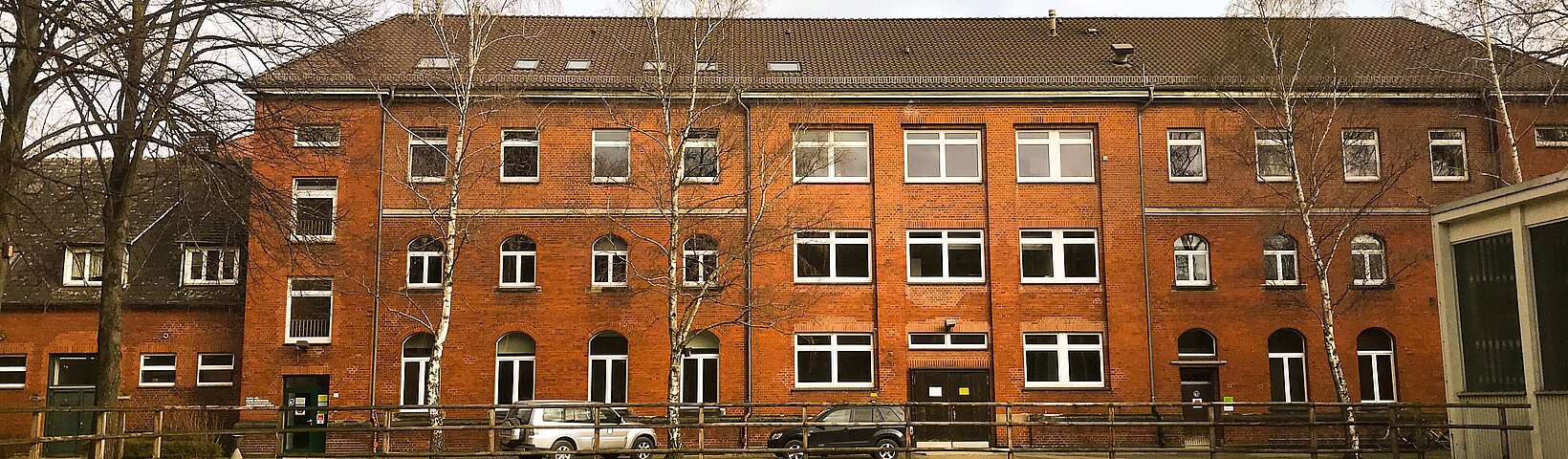 Frontansicht der Klinik für kleine Klauentiere; ein dreistöckiger Bachsteinbau mit Birken am linken und rechten Bildrand 