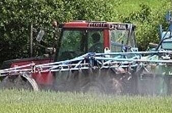 A tractor spreads pesticides