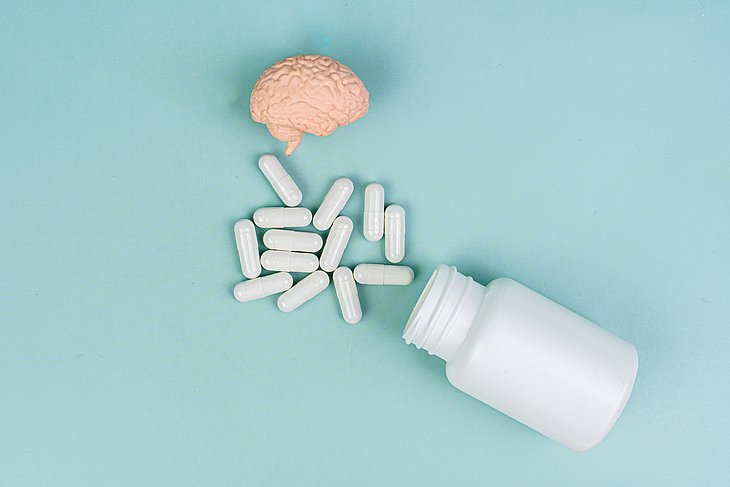 Gehirn und Tabletten auf blauem Hintergrund.