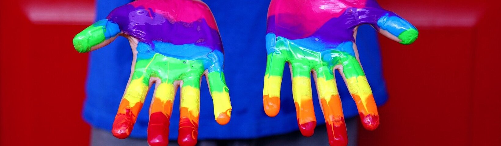 Kinderhände in den Farben des Regenbogens angemalt Kinderhände in den Farben des Regenbogens angemalt