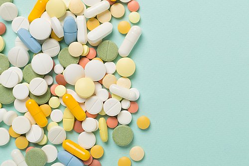Verschiedene Medikamente in Form von Tabletten und Kapseln vor einem farbigen Hintergrund.