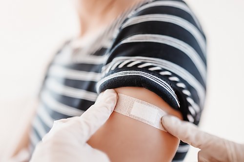 Blick auf den Arm einer Frau, auf dem nach einer Impfung ein Pflaster klebt.