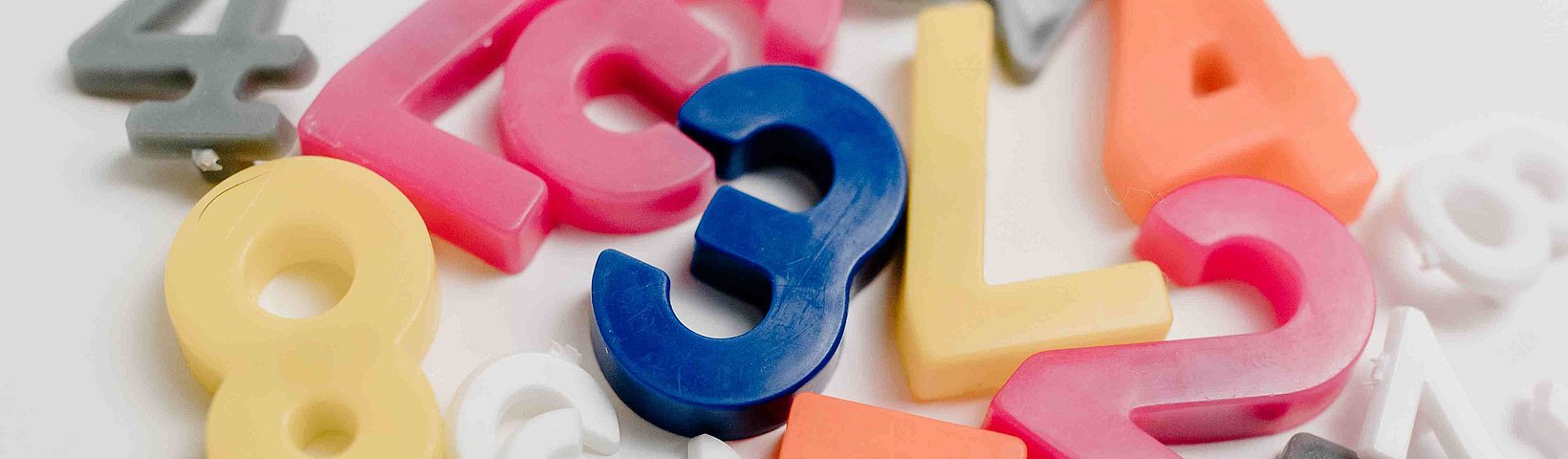 Bunte Ziffern wahllos auf Tisch liegend 