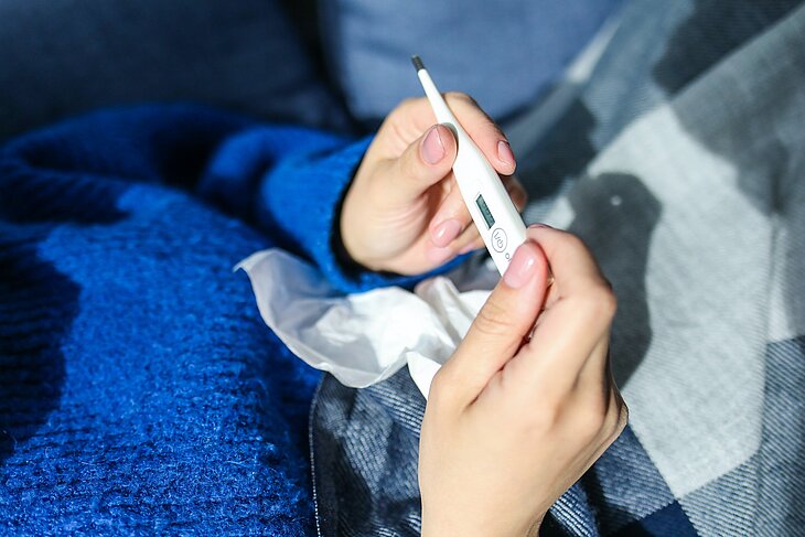 Ein Mensch hält ein Fieberthermometer