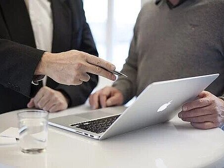 Stehtisch mit Laptop und zwei Personen