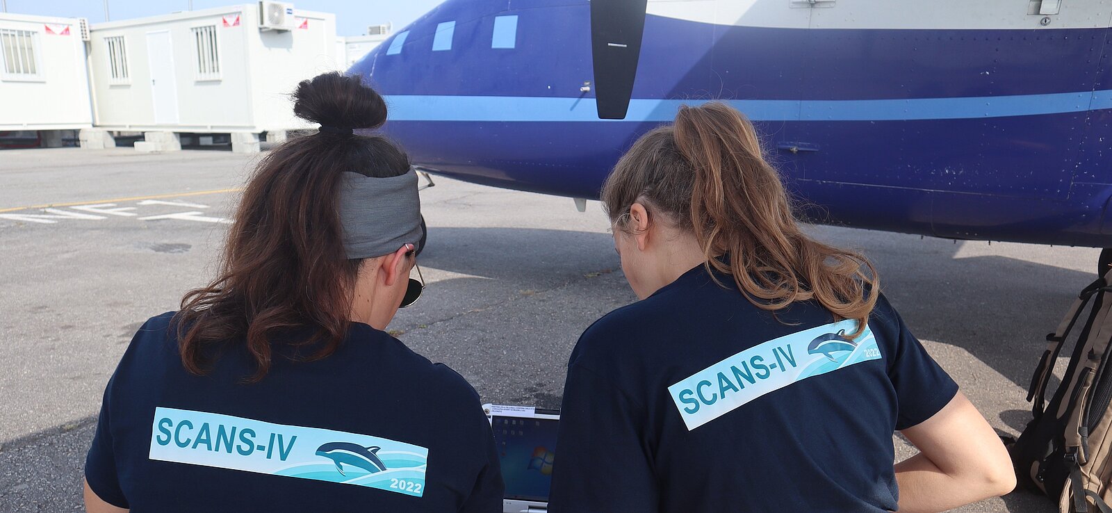 two scientists in front of a plane, planning the survey