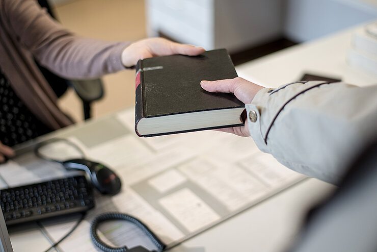 [Translate to English:] Ausleihvorgang an der Bibliothestheke