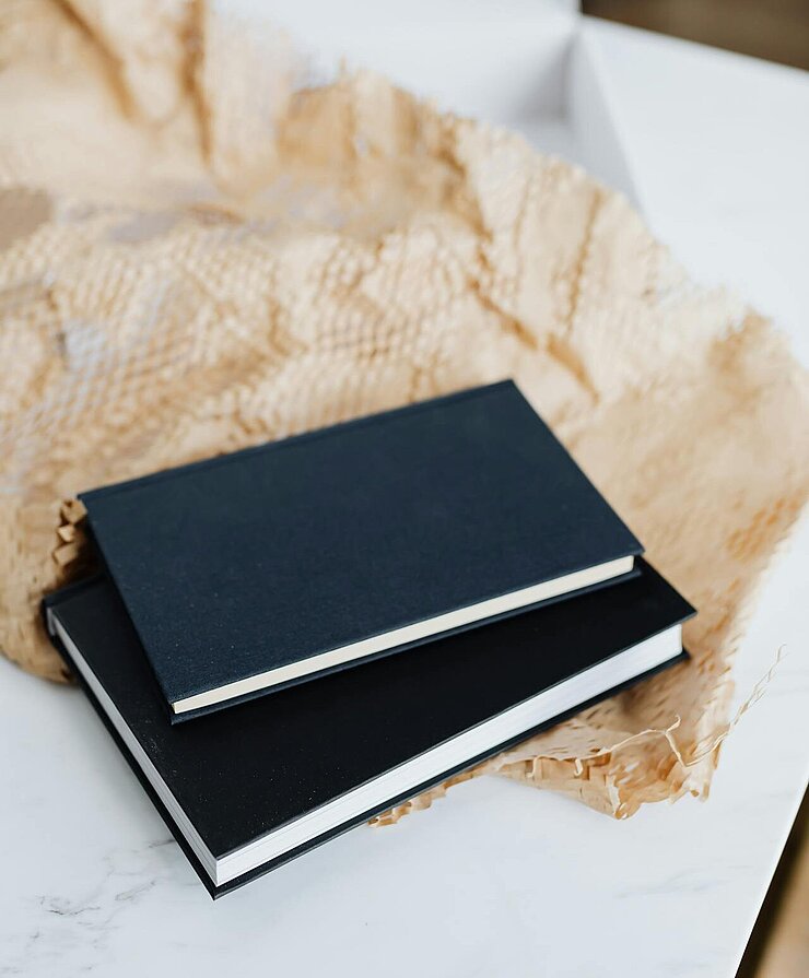Zwei unterschiedliche große Bücher liegen auf einem zerknitterten Papier.