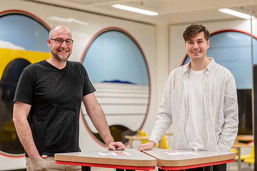 Daniel Todt und André Gömer stehen gemeinsam an einem Stehtisch.